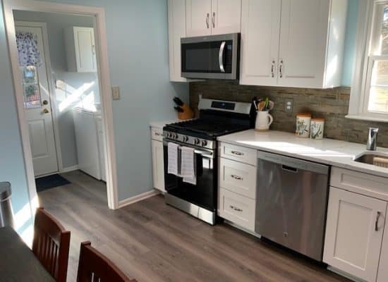 kitchen makeover, baby blue walls and white cupboards with black appliances and wooden floors